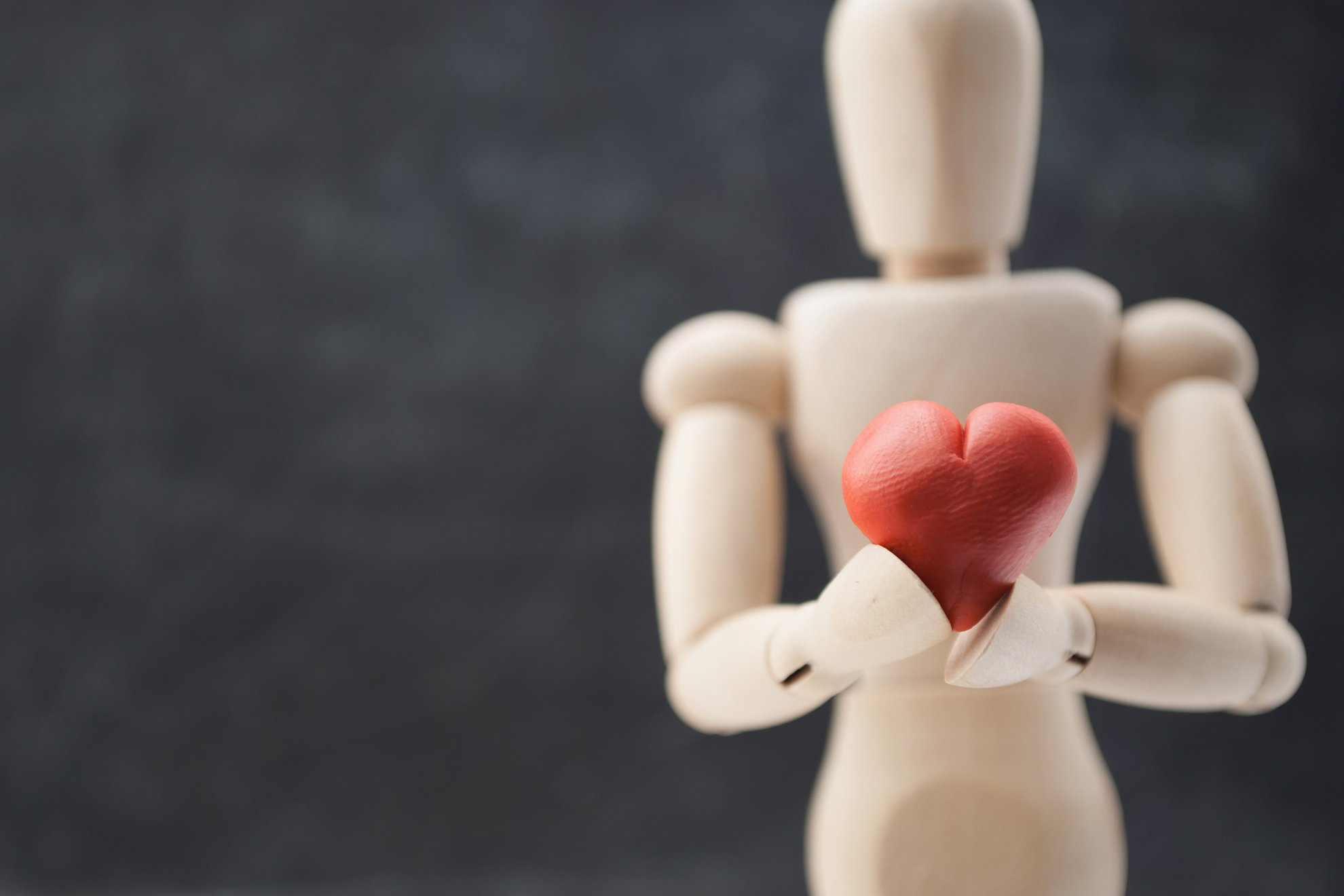 Classic wooden dummy holds red little heart for Valentine’s Day.